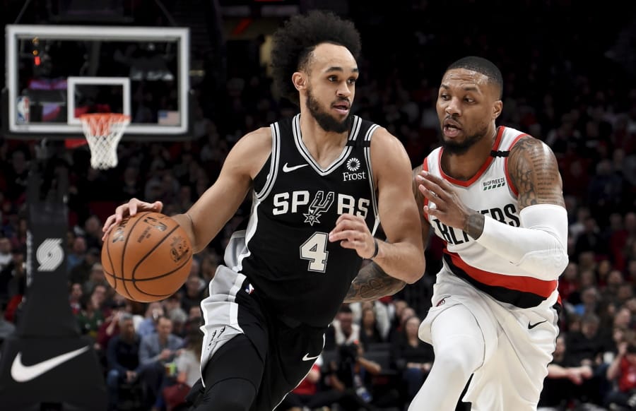 San Antonio Spurs guard Derrick White, left, drives to the basket against Portland Trail Blazers guard Damian Lillard, right, during the first half of an NBA basketball game in Portland, Ore., Thursday, Feb. 6, 2020.