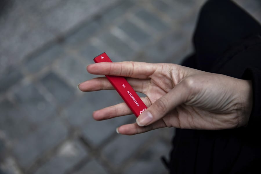 A woman holds a Puff Bar disposable vape device.