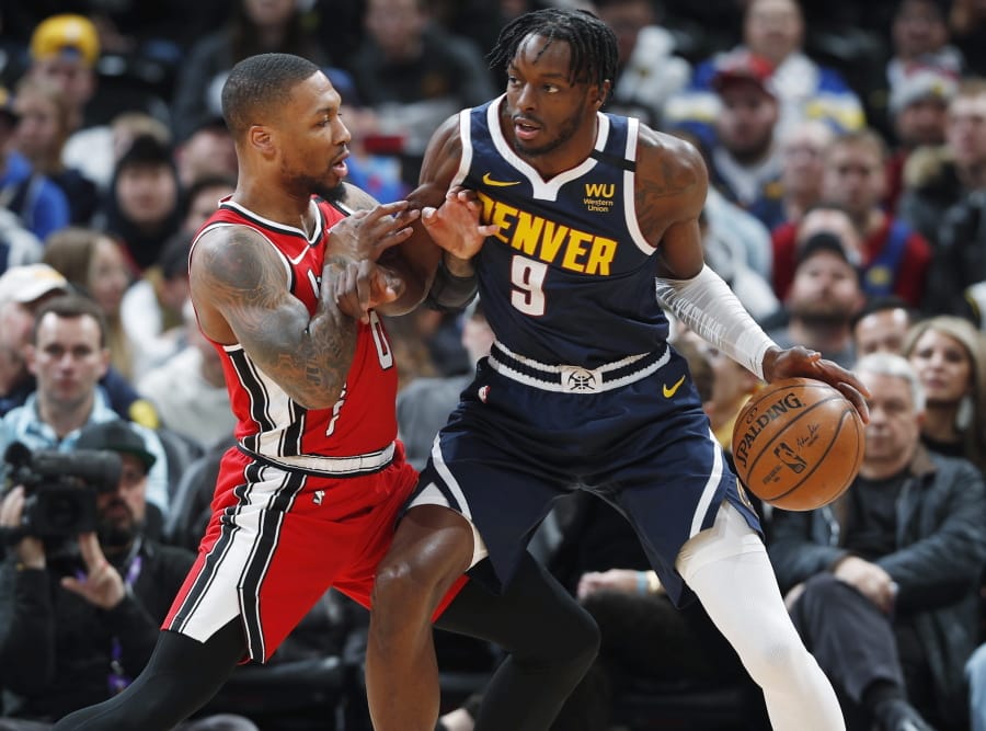 Denver Nuggets forward Jerami Grant, right, works the ball inside as Portland Trail Blazers guard Damian Lillard defends in the first half of an NBA basketball game Tuesday, Feb. 4, 2020, in Denver.