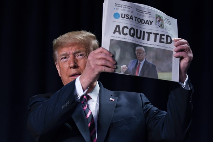 President Donald Trump holds up a newspaper with the headline that reads &quot;ACQUITTED&quot; at the 68th annual National Prayer Breakfast, at the Washington Hilton, Thursday, Feb. 6, 2020, in Washington.