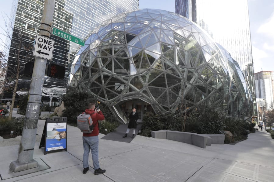 Mathis Koos, left, takes a photo of his partner, Valery Freyman, in front of the Amazon Spheres, Wednesday in Seattle. The couple arrived Tuesday from Orlando, Fla., for a weeklong vacation and said the outbreak of the coronavirus in the Seattle area did not deter them from their plans. (ted s.