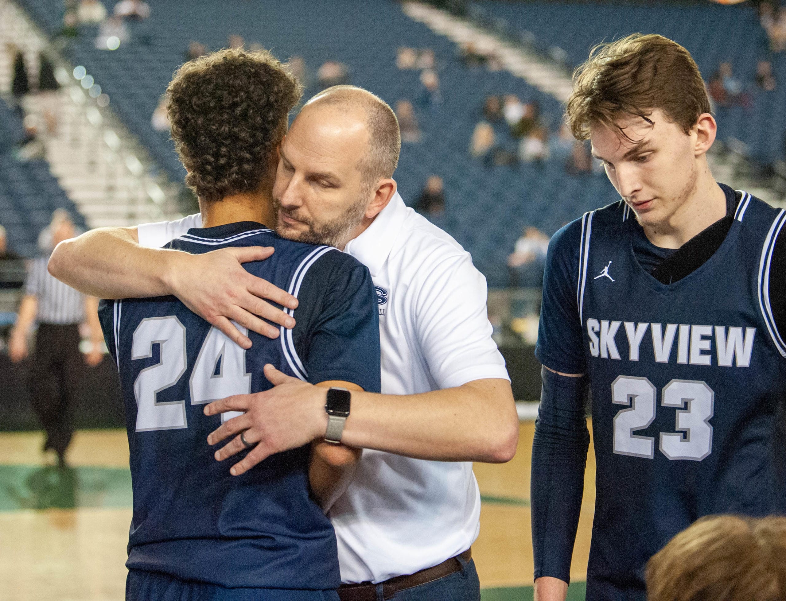 Skyview's Jace Chatman receives a hug from coach Matt Gruhler in a 4A State consolation game Friday at the Tacoma Dome. Skyview lost 75-55 to Olympia to end its season.