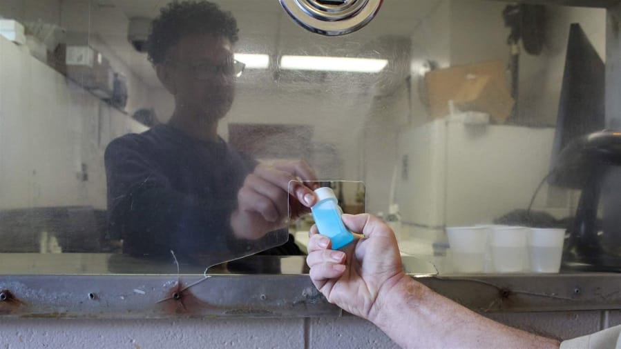 Nurse John Sepulveda demonstrates how he hands inmates their daily doses of methadone at a Rhode Island Department of Corrections prison in Cranston. Nationwide, more prisons and jails are starting to offer inmates methadone and buprenorphine for the treatment of opioid addiction. (Courtesy of the Rhode Island Department of Corrections/TNS)
