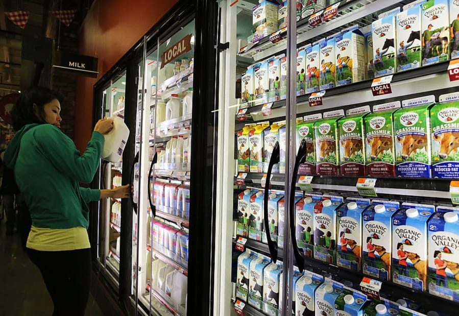 A customer selects milk at a Brooklyn supermarket in New York City on June 9, 2014. Defining &quot;milk&quot; has become more complicated and contentious as almond, oat, soy and other plant-based alternatives compete for customers.
