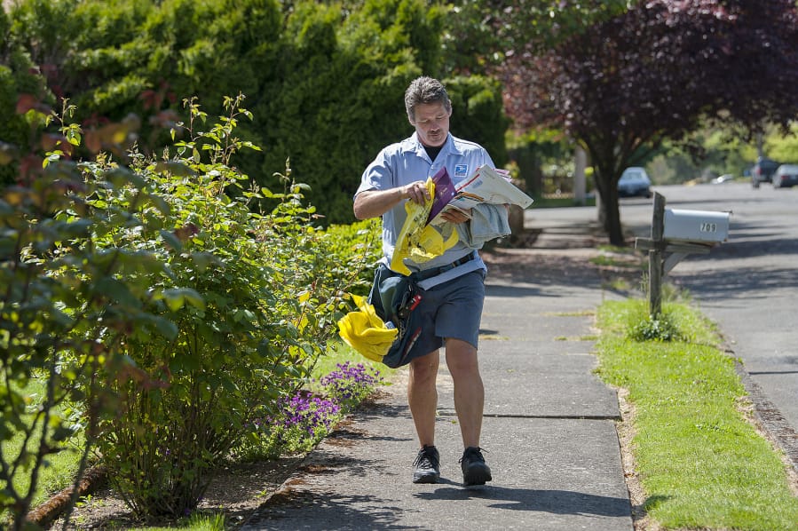 Letter carrier Bob Weyer delivers mail and a yellow bag for the National Letter Carriers Food Drive to residents in the Carter Park neighborhood 2017. This year&#039;s food drive has been canceled.