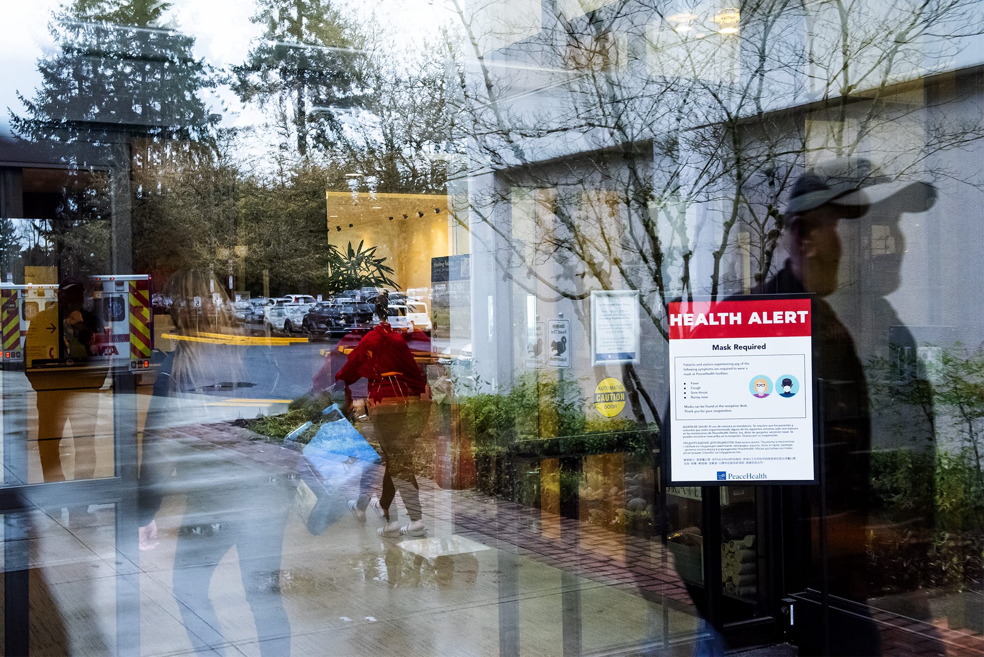 Visitors walk past a health alert sign with measures meant to prevent the spread of coronavirus at an entrance to PeaceHealth Southwest Medical on Monday afternoon, March, 2, 2020.