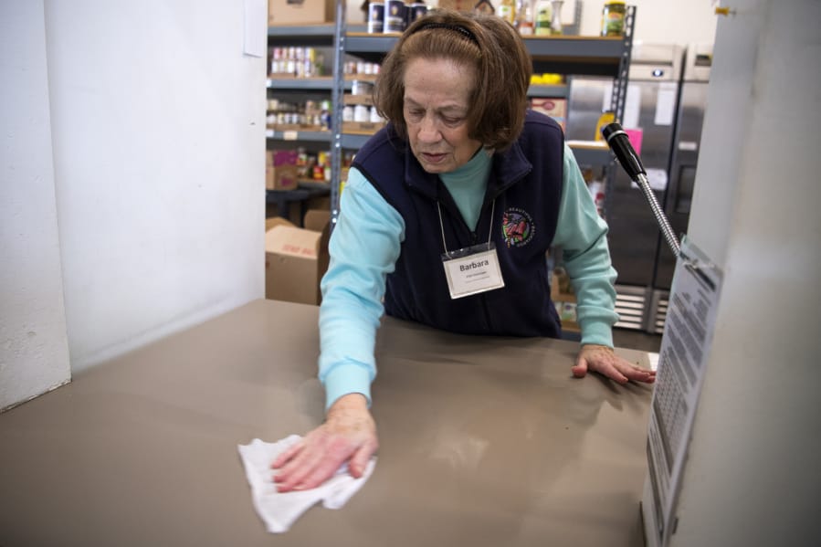 Volunteer Barbara Samuels disinfects the counter at FISH Westside Food Pantry of Vancouver on Tuesday. The food bank is taking extra precautions to keep everything clean in response to the coronavirus.