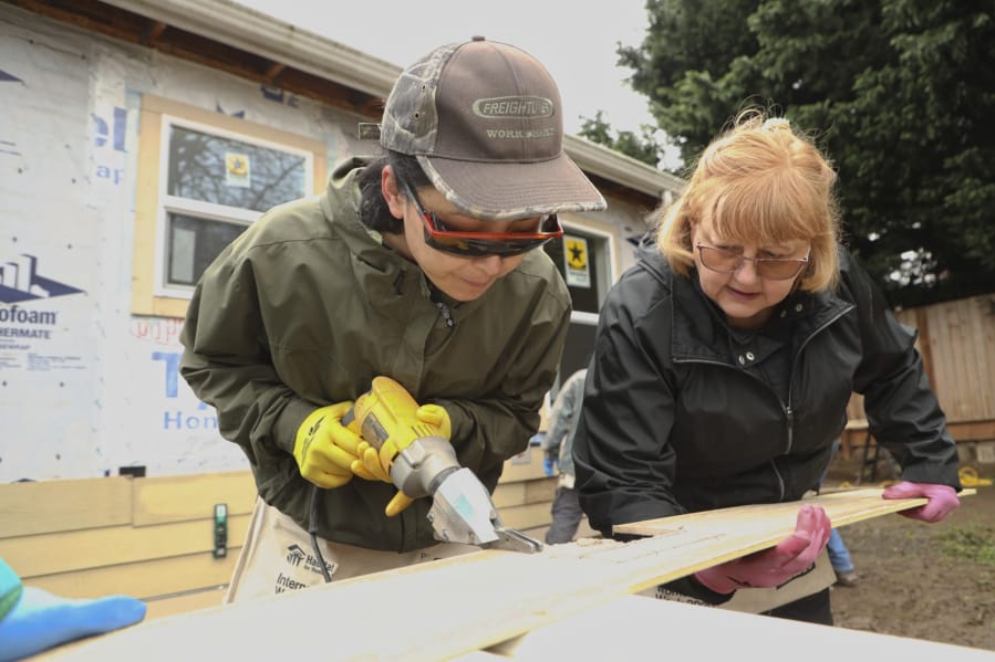 Tsering Wangden, left, and Sharon McConnell, right, volunteer on a construction site as part of Habitat for Humanity International Women Build Week 2020 on Saturday. About a dozen women worked on the site, preparing it for future resident Ting Mangshang and his family.