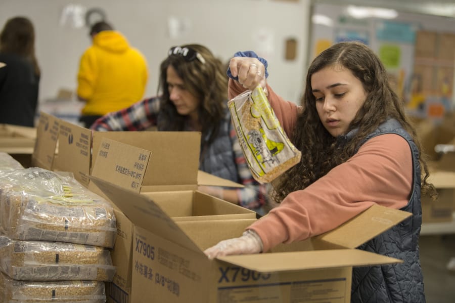 Volunteers Kirsten Humber, left, and her daughter, Delaney, 16, help put together emergency food boxes at the Clark County Food Bank on Wednesday afternoon.