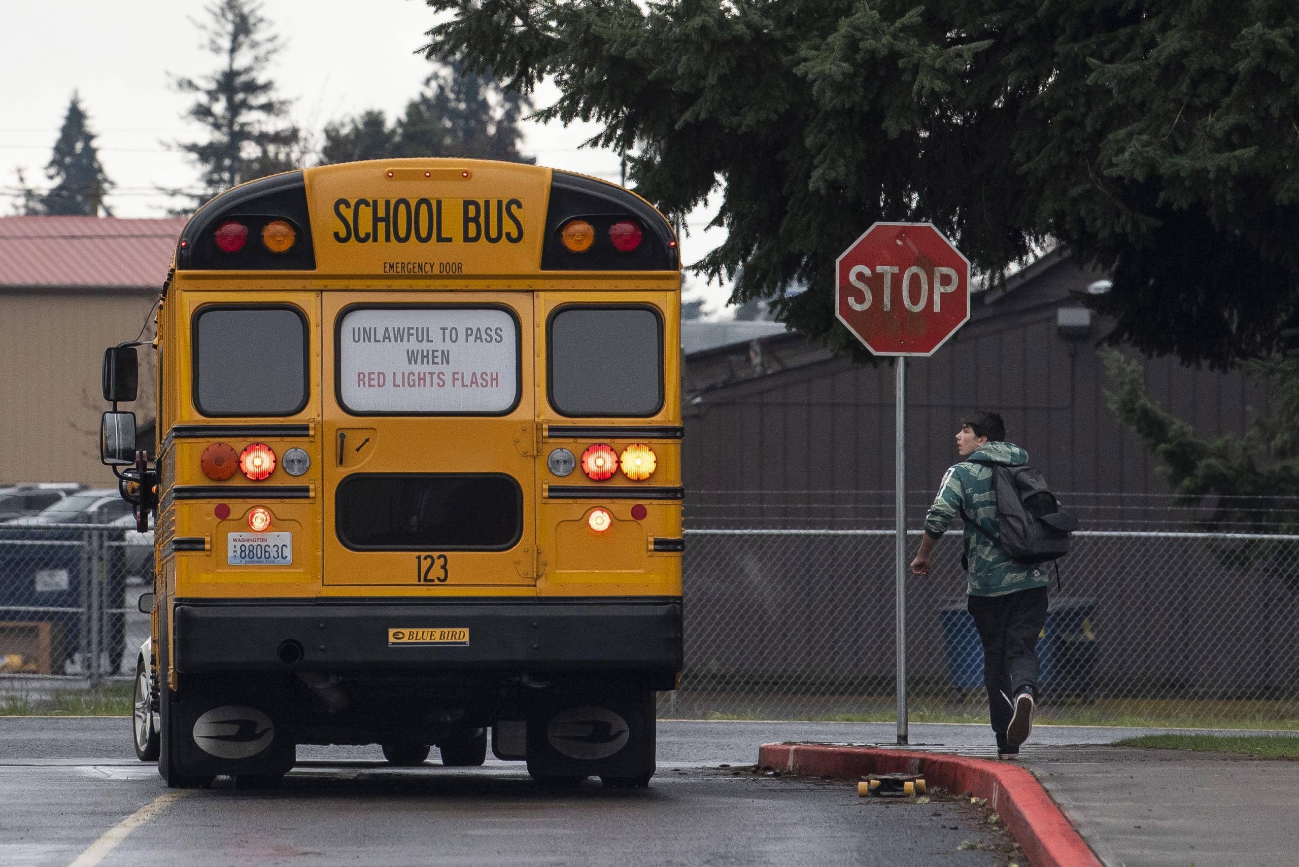 Owen Watt runs along side a school bus filled with fellow students as it pulls away from Covington Middle School on Friday afternoon, March 13, 2020.