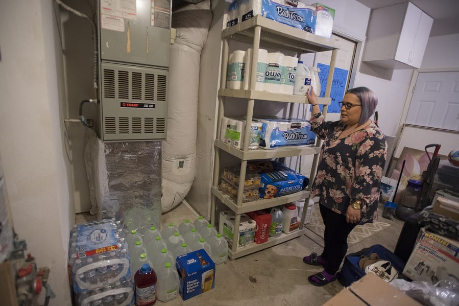 Cecilia Jones of Vancouver looks over her supply of water and paper goods in her garage Monday afternoon. Jones and her family, who have enough supplies to support themselves for a month, have been monitoring the news since the end of February and started piecing together supplies bit by bit. &quot;We&#039;re just trying to prepare not to leave,&quot; Jones said.