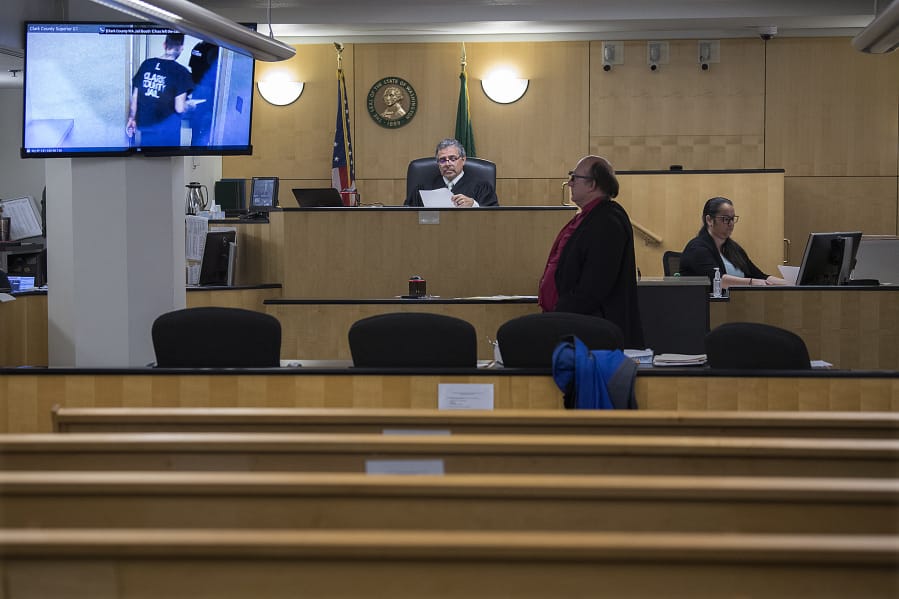 Judge Gregory Gonzales presides over a nearly empty courtroom while joined by attorney Jeff Sowder during first appearances in Clark County Superior Court on Tuesday morning. Gonzales was able to see and talk to the defendants through live video from the jail, a precaution being employed due to the COVID-19 pandemic.