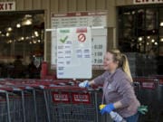 Taunya Gough, a cashier and assistant at the northeast Vancouver Costco, shares a smile with a colleague while disinfecting the handles of shopping carts on March 20.