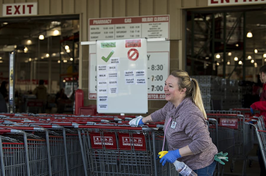 Taunya Gough, a cashier and assistant at the northeast Vancouver Costco, shares a smile with a colleague while disinfecting the handles of shopping carts on March 20.