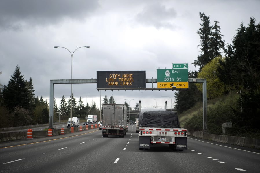 Trucks drive under a sign on Interstate 5 reading &quot;Stay home, limit travel&quot; in Vancouver on Tuesday. Transportation is one segment not impacted as deeply, although airlines are hurting.
