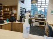 A bottle of disinfectant is seen on the front desk of the library at Washington State University Vancouver as junior Travis Lynn works nearby amid concerns of COVID-19 on Wednesday morning. Campus closed Wednesday afternoon following Gov. Jay Inslee&#039;s &quot;Stay Home, Stay Healthy&quot; order to stop the spread of COVID-19.