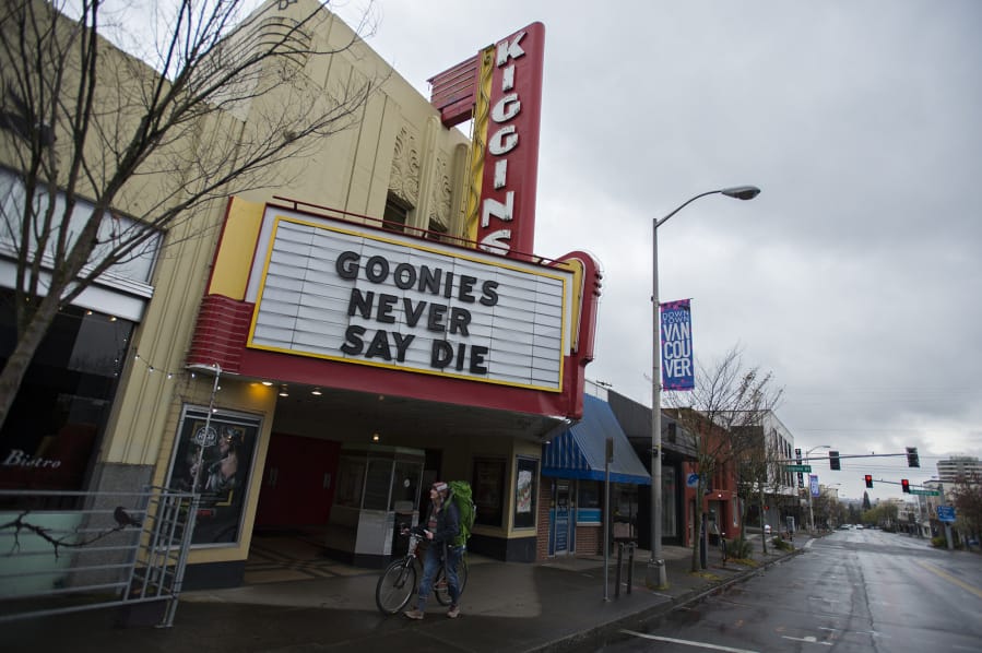 Vancouver resident Elizabeth Hay walks her bike past Kiggins Theatre on a nearly empty Main Street on Friday morning. Kiggins is currently closed but has partnered with an independent film streaming service.