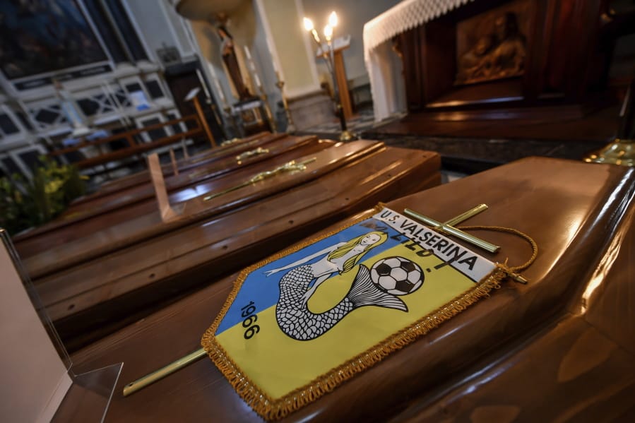 Coffins, one of them with the pennant of the local soccer team, wait to be transported to cemetery, in the church of Serina, near Bergamo, Northern Italy, Saturday, March 21, 2020. Italy&#039;s tally of coronavirus cases and deaths keeps rising, with new day-to-day highs: 793 dead and 6,557 new cases. For most people, the new coronavirus causes only mild or moderate symptoms. For some it can cause more severe illness.