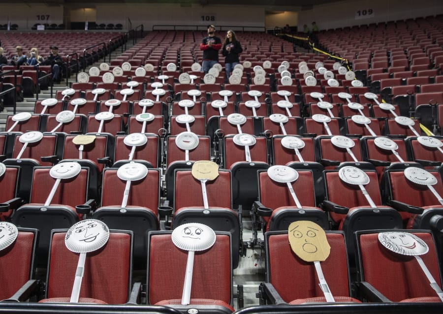 The Auburn fan section got creative by placing paper plate faces on the seats during the Class 1C boys high school basketball tournament championship game against Ogallala at Pinnacle Bank Arena, Saturday, March 14, 2020, in Lincoln, Neb. Crowds were limited to staff and immediate family due to concerns over the coronavirus. For most people, the new coronavirus causes only mild or moderate symptoms. For some it can cause more severe illness, especially in older adults and people with existing health problems.