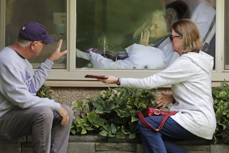Judie Shape, center, who has tested positive for the coronavirus, blows a kiss to her son-in-law, Michael Spencer, left, as Shape&#039;s daughter, Lori Spencer, right, looks on, Wednesday, March 11, 2020, as they visit on the phone and look at each other through a window at the Life Care Center in Kirkland, Wash., near Seattle. In-person visits are not allowed at the nursing home.  The vast majority of people recover from the new coronavirus. According to the World  Health Organization, most people recover in about two to six weeks, depending on the severity of the illness. (AP Photo/Ted S.