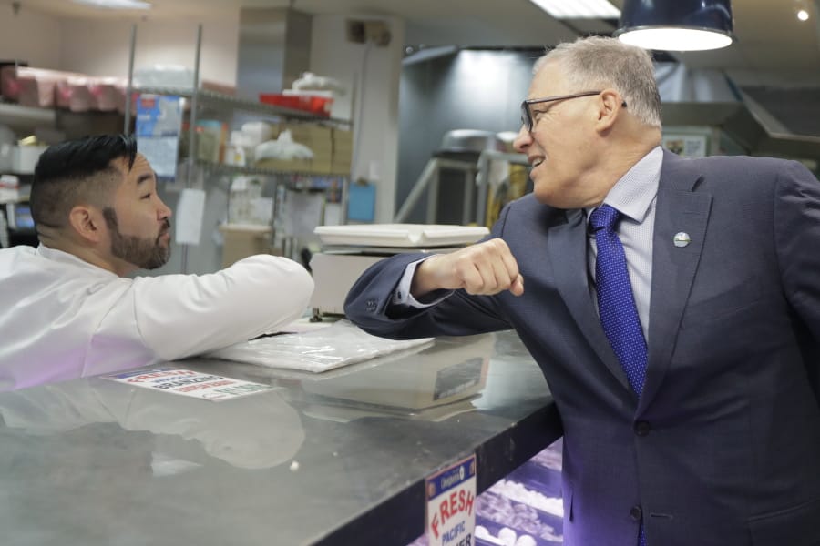 Washington Gov. Jay Inslee, right, bumps elbows with a worker at the seafood counter of the Uwajimaya Asian Food and Gift Market, Tuesday, March 3, 2020, in Seattle&#039;s International District. Inslee said he&#039;s doing the elbow bump with people instead of shaking hands to prevent the spread of germs, and that his visit to the store was to encourage people to keep patronizing businesses during the COVID-19 Coronavirus outbreak. Earlier in the day, following a tour at a health clinic, Inslee urged people to wash hands frequently and practice other measures of health hygiene, and to stay home from work and public events if they don&#039;t feel well or have any symptoms of illness. (AP Photo/Ted S.