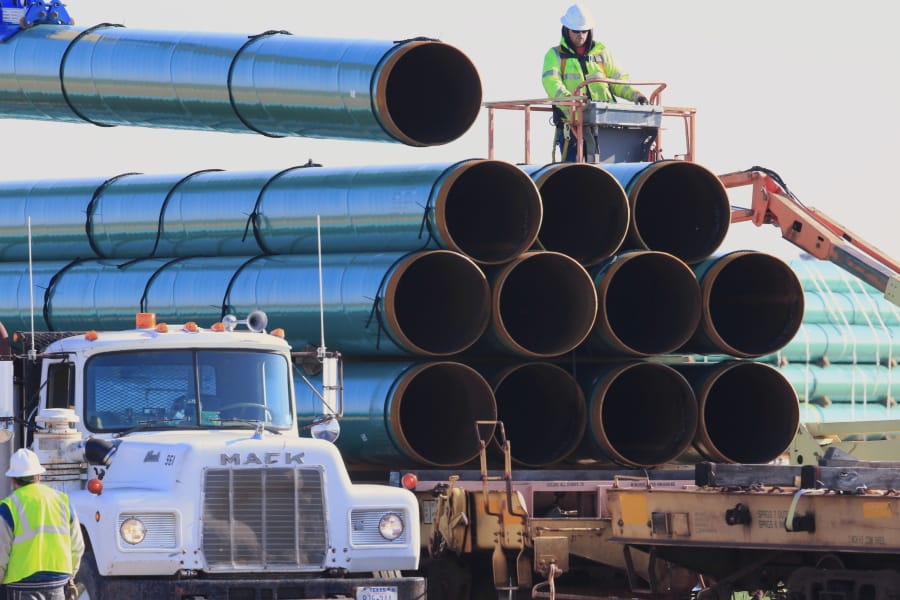 FILE - In this May 9, 2015, file photo, workers unload pipes in Worthing, S.D., for the Dakota Access oil pipeline that stretches from the Bakken oil fields in North Dakota to Illinois. A federal judge on Wednesday, March 25, 2020, ordered the U.S. Army Corps of Engineers to conduct a full environmental review of the Dakota Access pipeline, nearly three years after it began carrying oil.