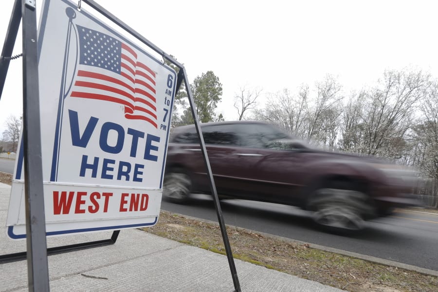 A car passes a polling precinct during the Democratic Presidential primary voting Tuesday, March 3, 2020, in Richmond, Va.