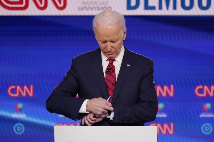Former Vice President Joe Biden, check his watch during a commercial break as he participates in a Democratic presidential primary debate at CNN Studios, Sunday, March 15, 2020, in Washington.