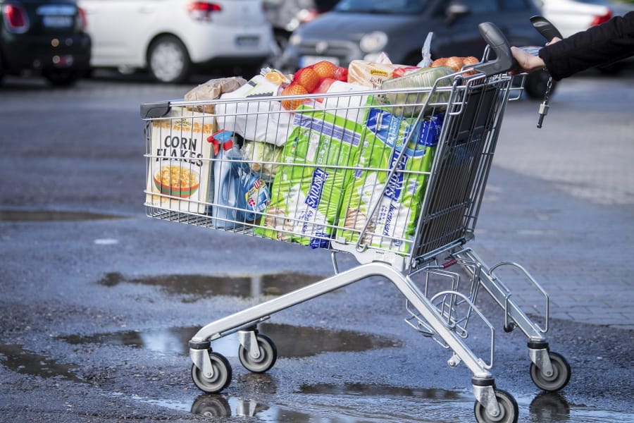 A customer pushes a shopping trolley filled to the brim across the parking lot of a supermarket in Pullach, Germany, Friday, March 13, 2020. For most people, the new coronavirus causes only mild or moderate symptoms, such as fever and cough. For some, especially older adults and people with existing health problems, it can cause more severe illness, including pneumonia.