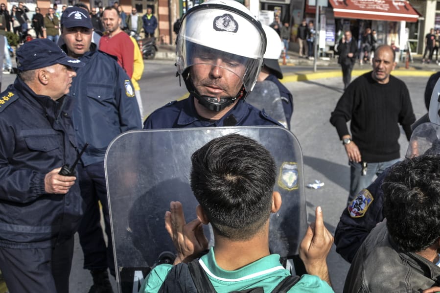 A migrant speaks to a Greek policeman during minor clashes Tuesday at the port of Mytilene, Greece, after locals blocked access to the Moria refugee camp on the Aegean island of Lesbos.