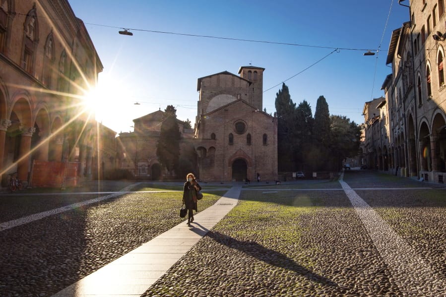 A woman walks past the Basilica of Santo Stefano, in Bologna, Italy, Wednesday, March 11, 2020. In Italy the government extended a coronavirus containment order previously limited to the country&#039;s north to the rest of the country beginning Tuesday, with soldiers and police enforcing bans. For most people, the new coronavirus causes only mild or moderate symptoms, such as fever and cough. For some, especially older adults and people with existing health problems, it can cause more severe illness, including pneumonia.