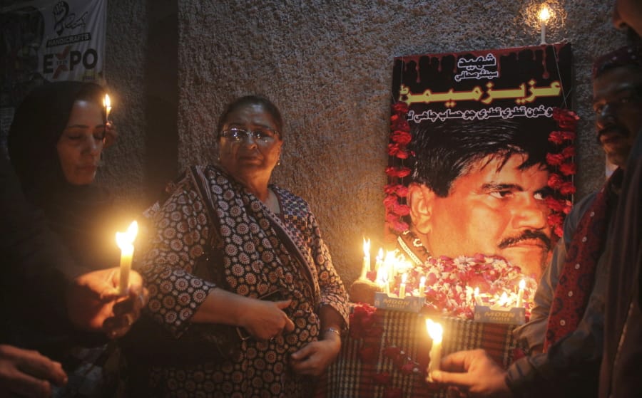 In this Oct. 17, 2020, photo, Pakistani civil society activists hold candle vigil to pay tribute to Aziz Memon in Hyderabad, Pakistan. In Pakistan, being a dissident or even raising a critical voice is dangerous business. Rights groups say that despite the election in 2018 of a civilian government, the army still rules from behind with an iron fist.