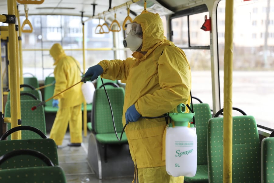 Employees wearing protective gear spray disinfectant to sanitize a passenger bus as a preventive measure against the coronavirus in Lviv, Ukraine, Tuesday, March 3, 2020. Ukrainian Chief sanitary and epidemiological doctor Viktor Liashko has just reported its first confirmed case of the new COVID-19 coronavirus, saying a man who recently arrived from Italy was diagnosed with the virus.