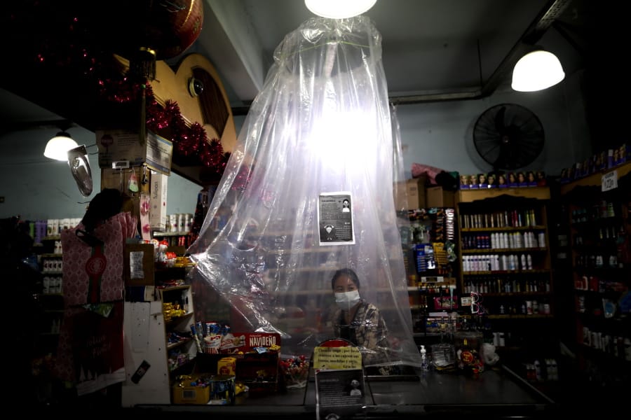 A supermarket cashier waits for costumers behind a makeshift plastic curtain as a precaution against the spread of the new coronavirus, in Buenos Aires, Argentina, Monday, March 16, 2020. For most people, the new coronavirus causes only mild or moderate symptoms, such as fever and cough. For some, especially older adults and people with existing health problems, it can cause more severe illness, including pneumonia.