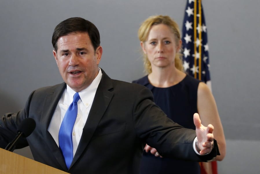 Arizona Gov. Doug Ducey, left, answers a question as he is joined by Arizona Department of Health Services Director Dr. Cara Christ, right, as they provide an update on the coronavirus outbreak during a news conference at the Arizona State Public Health Laboratory Monday, March 23, 2020, in Phoenix. (AP Photo/Ross D.