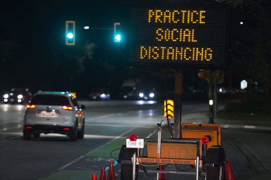 FILE - In this Wednesday, March 18, 2020 file photo, a sign reminding people about &quot;social distancing&quot; in the midst of the COVID-19 coronavirus outbreak stands next to a roadway in North Vancouver, British Columbia, Canada. Many see &quot;social distancing&quot; to be the greatest pandemic-era addition the vernacular yet -- easily understood phrasing that&#039;s helped communicate to millions that they need to keep a safe berth to avoid spreading the virus.