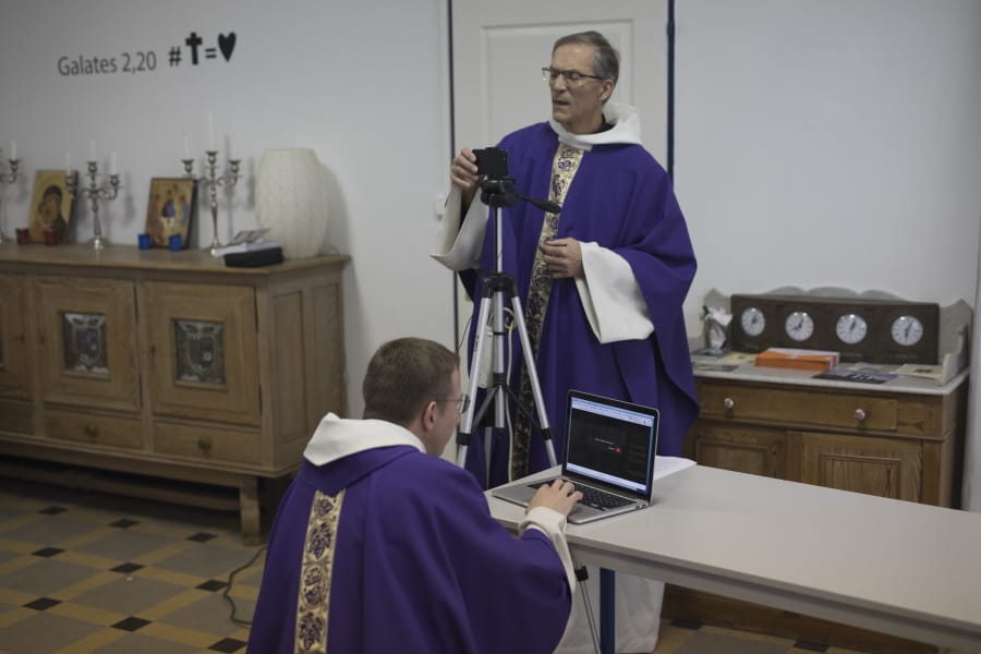 Priest Philippe Rochas, left, and Jean-Benoit de Beauchene pack up livestreaming equipment after holding a closed door Sunday mass at the St. Vincent de Paul church in Marseille, southern France, Sunday.