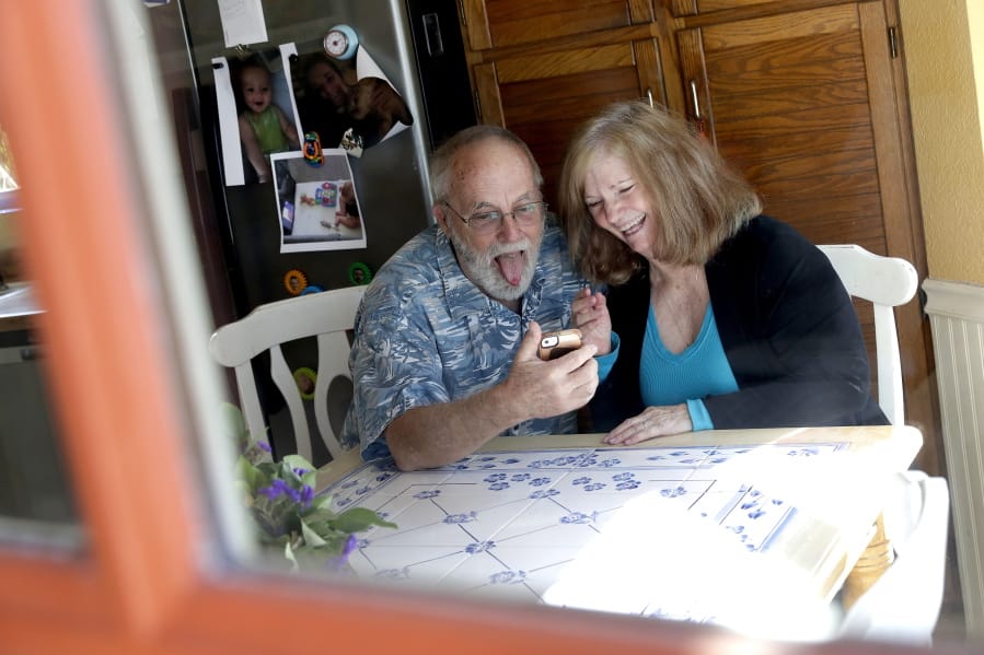 Seen through their kitchen window, Allan and Debbie Cameron contact their grandchildren via the internet Wednesday, March 25, 2020, in Chandler, Ariz. Debbie, 68, has asthma which makes her one of the people most at risk from the new coronavirus. The Cameron&#039;s now she see their children and grandchildren from the other side of a window or a phone.