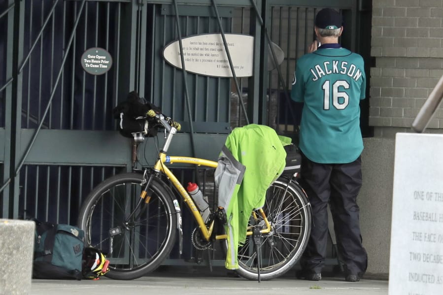 Al Jackson, a die-hard Seattle Mariners fan and 11-year season ticket holder, takes a photo through the bars at the home plate entrance of T-Mobile Park in Seattle, Thursday, March 26, 2020, around the time when the Mariners&#039; Opening Day baseball game against the visiting Texas Rangers would have started. Earlier in the month, Major League Baseball called off the start of the season due to the outbreak of the new coronavirus, but Jackson said he still felt he needed to be down at the ballpark just the same. (AP Photo/Ted S.
