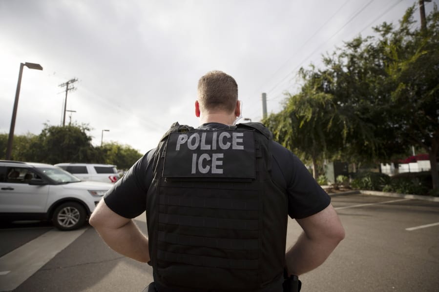 FILE - In this July 8, 2019, file photo, a U.S. Immigration and Customs Enforcement (ICE) officer looks on during an operation in Escondido, Calif.  Pressure is mounting on the Trump administration to release people from immigration detention facilities where at least one detainee has already tested positive for COVID-19.