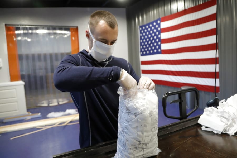In this Thursday, March 26, 2020 photo, A.J. Davidson, who works in the business development department at Blue Delta Jeans, packages face guards made at the jeans manufacturing site in Shannon, Miss. The company has shifted its operation from making custom jeans to help with the demand of face masks to combat the coronavirus outbreak. The new coronavirus causes mild or moderate symptoms for most people, but for some, especially older adults and people with existing health problems, it can cause more severe illness or death.