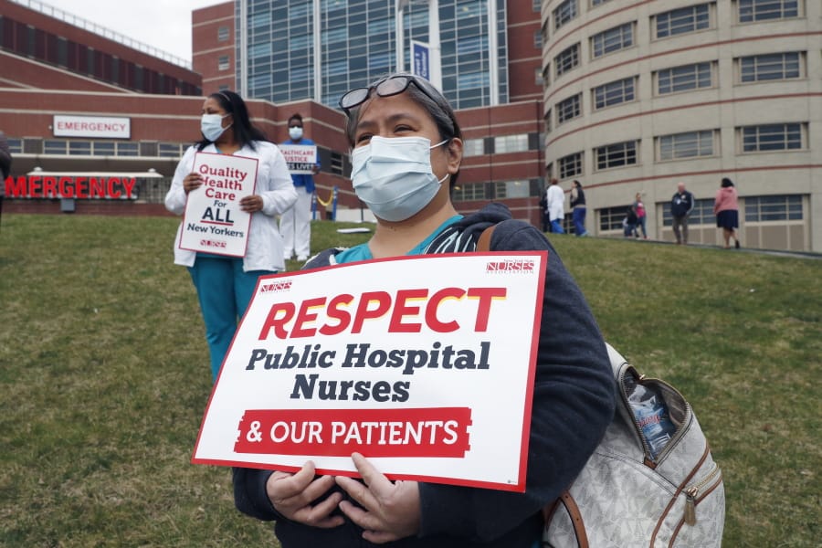 Nurses stand on a grassy hill outside the emergency entrance to Jacobi Medical Center in the Bronx borough of New York, Saturday, March 28, 2020, as they demonstrate with members of the New York Nursing Association in support of obtaining an adequate supply of personal protective equipment for those treating coronavirus patients. A member of the New York nursing community died earlier in the week at another New York hospital. The city leads the nation in the number of coronavirus cases. Nurses say they are having to reuse their protective equipment endangering patients and themselves.