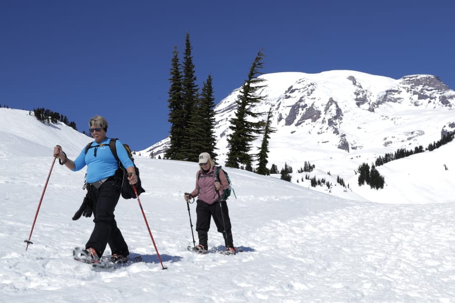 Danielle Kiechler, left, and Cathi Gouveia snowshoe above Paradise at Mount Rainier National Park, Wednesday, March 18, 2020, in Washington state. Most national parks are remaining open during the outbreak of the new coronavirus, but many are closing visitor centers, shuttles, lodges and restaurants in hopes of containing its spread. Both women work at schools in Puyallup, Wash., that are currently closed due to the virus outbreak. (AP Photo/Ted S. Warren) (ted s.