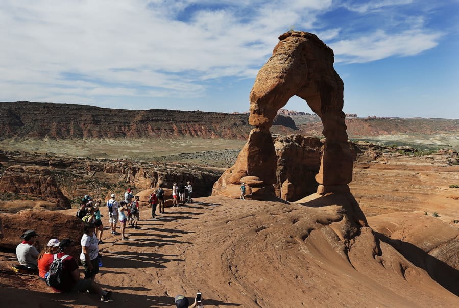 Tourists line up for photos June 3, 2016, at Delicate Arch in Arches National Park near Moab, Utah.