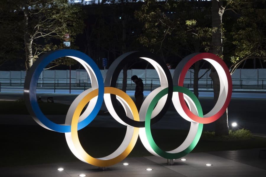 A man is seen through the Olympic rings in front of the New National Stadium in Tokyo, Tuesday. (Jae C.