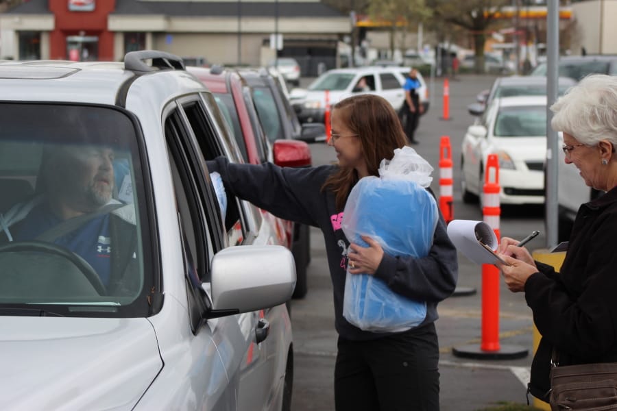 People from Salem Health Hospitals &amp; Clinics, hand out kits to make surgical masks causing a traffic jam in Salem, Ore., on Thursday, March 26, 2020. The plan is for citizens to make the masks, which take around a half-hour each to put together, and then drop the completed masks off. Hundreds of kits were handed out, enough to make more than 8,000 masks.