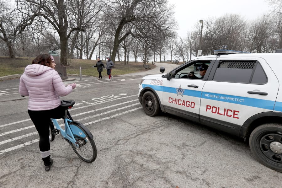 FILE - In this March 26, 2020, file photo, a Chicago police officer notifies a cyclist that the trails in Promontory Park, along Lake Michigan, are closed in an effort to limit the spread of COVID-19 infections, in Chicago. Chicago Mayor Lori Lightfoot&#039;s decision to shut down the trails along Lake Michigan and nearby parks during the coronavirus crisis underscores a growing concern that the large crowds of people flocking to beaches, parks and playgrounds are making it easier for the virus to spread.