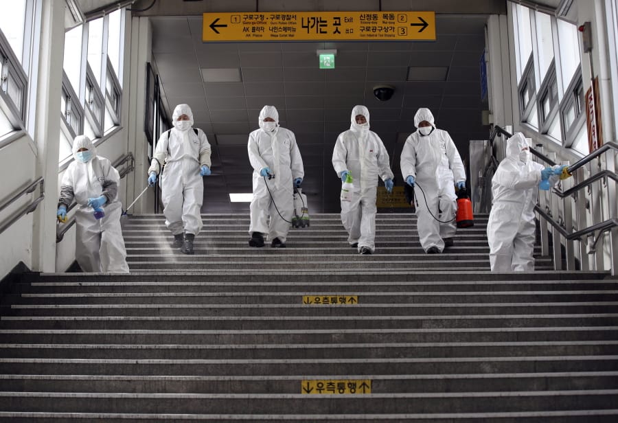 Workers wearing protective suits spray disinfectant as a precaution against the new coronavirus at a subway station in Seoul, South Korea, Thursday, March 12, 2020. For most people, the new coronavirus causes only mild or moderate symptoms, such as fever and cough.