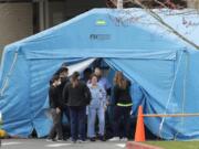 Workers exit a large tent set up in front of the emergency room at EvergreenHealth Medical Center, Tuesday, March 17, 2020, in Kirkland, Wash., near Seattle. In the area that has led the country in COVID-19 coronavirus cases and also across the country, hospitals are gearing up for an onslaught of coronavirus patients, but staff on the front lines are stretched thin and don&#039;t have the equipment they need to protect themselves from the highly contagious virus. (AP Photo/Ted S.