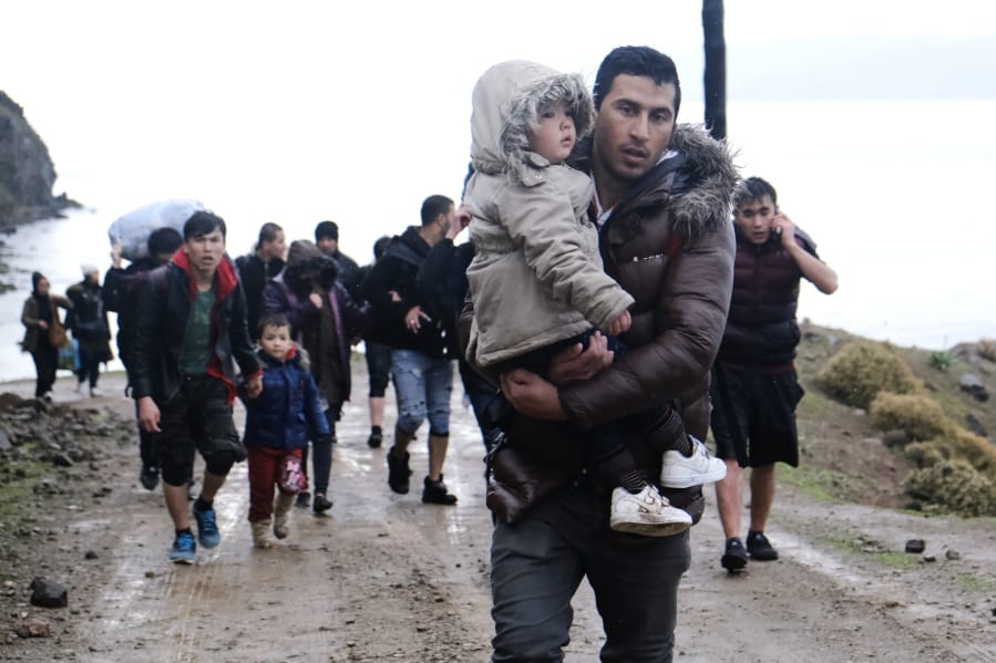 FILE  - In this March 5 2020 file photo, migrants walk to the village of Skala Sikaminias, on the Greek island of Lesbos, after crossing on a dinghy the Aegean sea from Turkey on Thursday, March 5, 2020. No entry, says Hungary. Move along, says Greece. Watch out, says Croatia: They might have the coronavirus. This week, thousands of asylum-seekers sit at the intersection of a pair of fast-moving news stories -- a spike in migration in Europe and uncertainty about the global spread of the new and sometimes deadly virus.